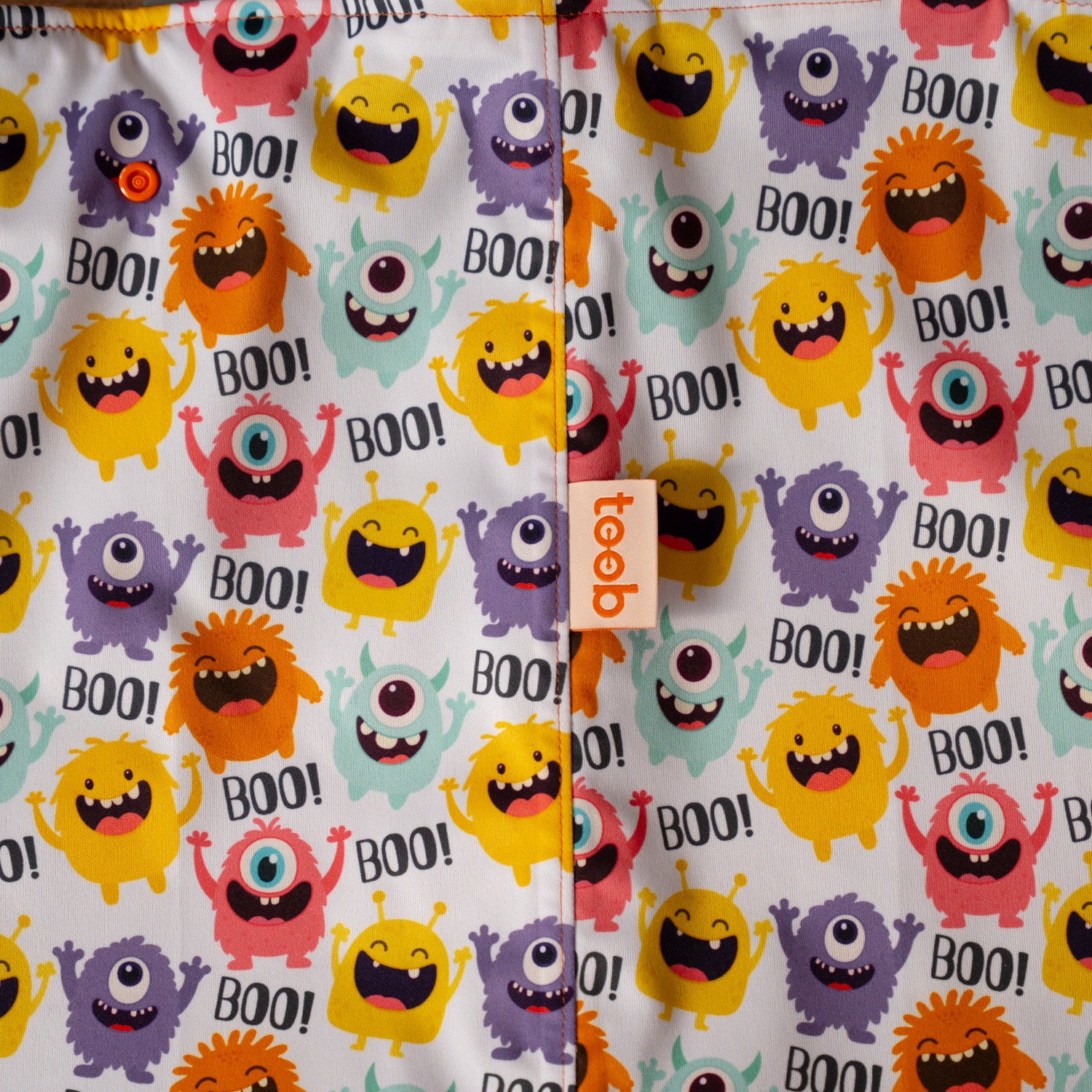 Fabric with colorful monster pattern and 'BOO!' text on a white background