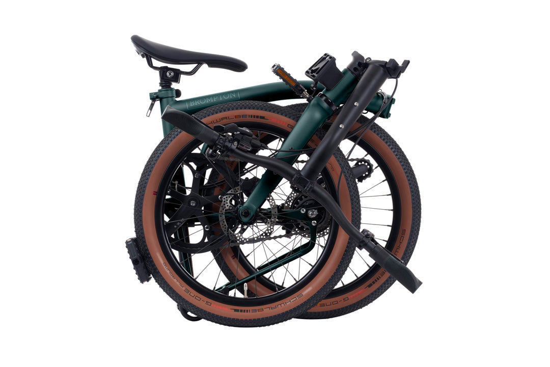 Brompton G Line Folded bicycle with green frame and brown tires on a white background