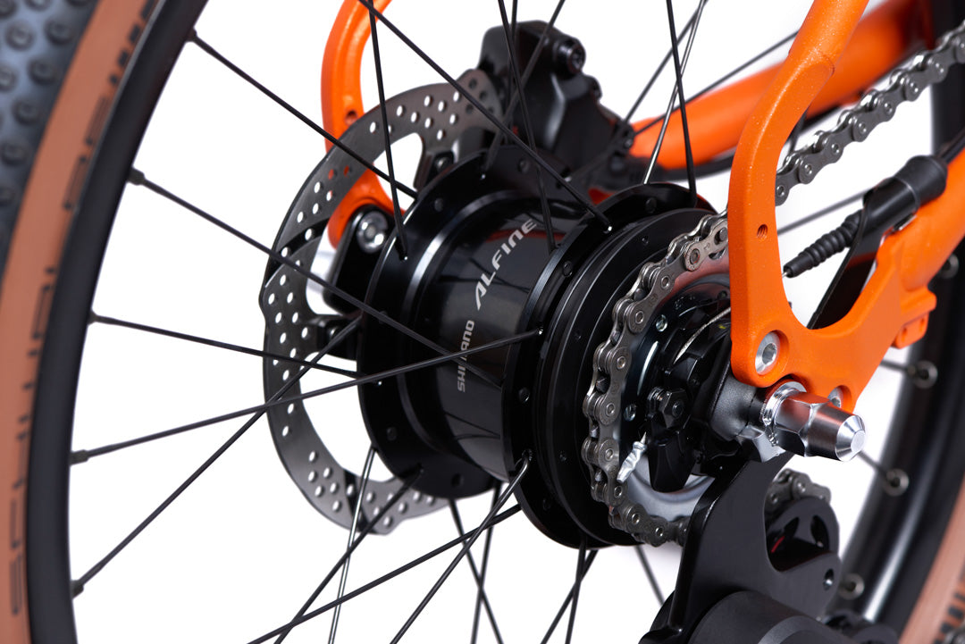 Brompton G Line Close-up of a bicycle wheel with orange frame and black hub gear on a white background
