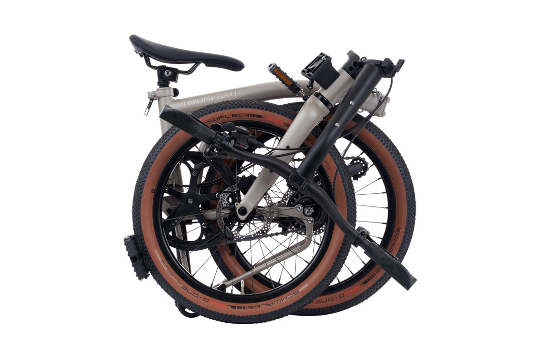 Brompton G Line Folded bicycle with brown tires on a white background