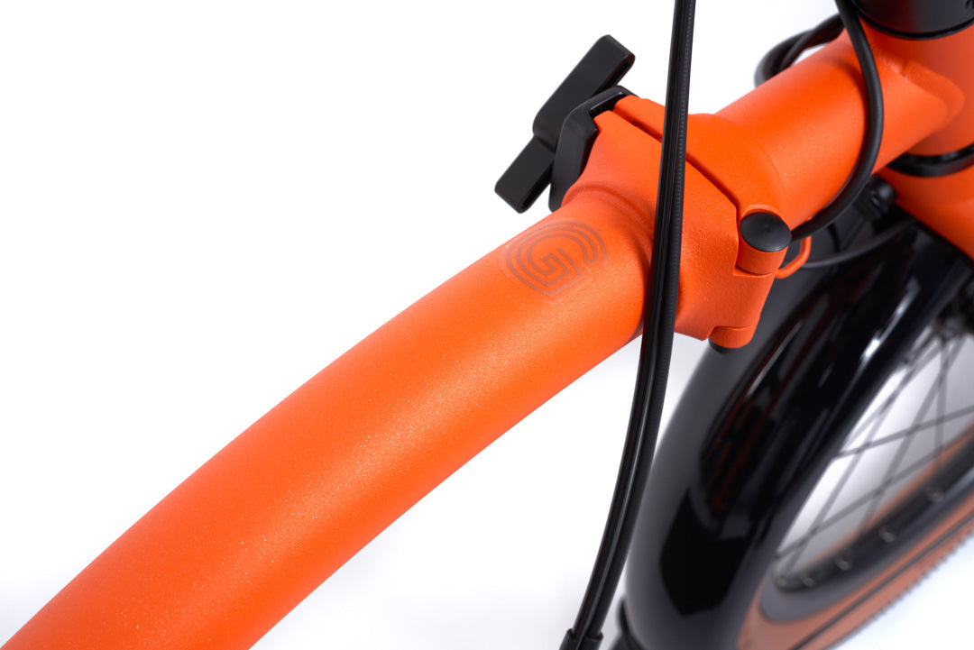 Brompton G Line Close-up of an orange bicycle handlebar with a black brake lever on a white background