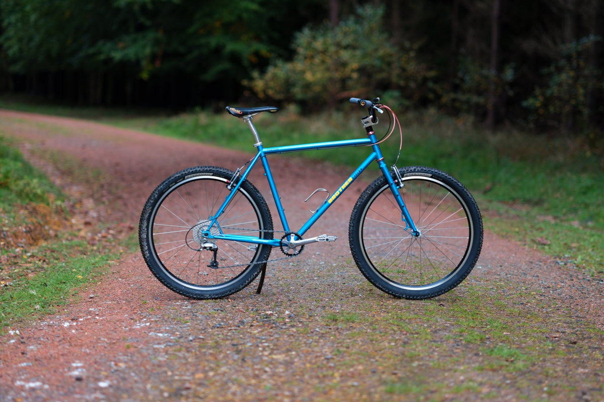 Blue bicycle on a dirt path with trees in the background